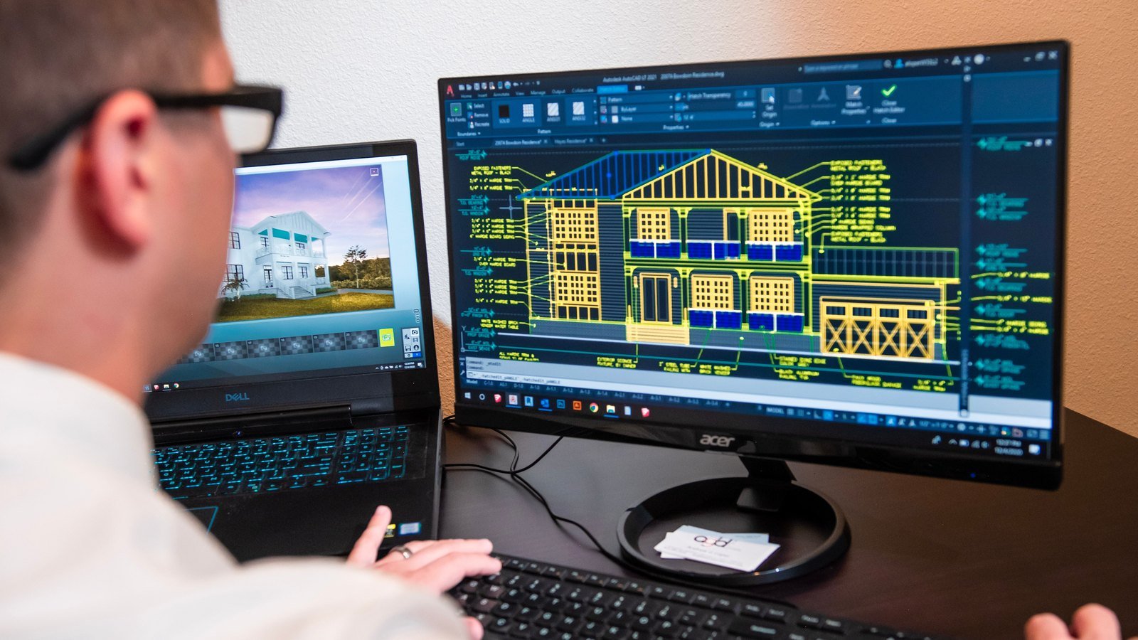 Technical designer reviewing detailed building drawings on computer monitors